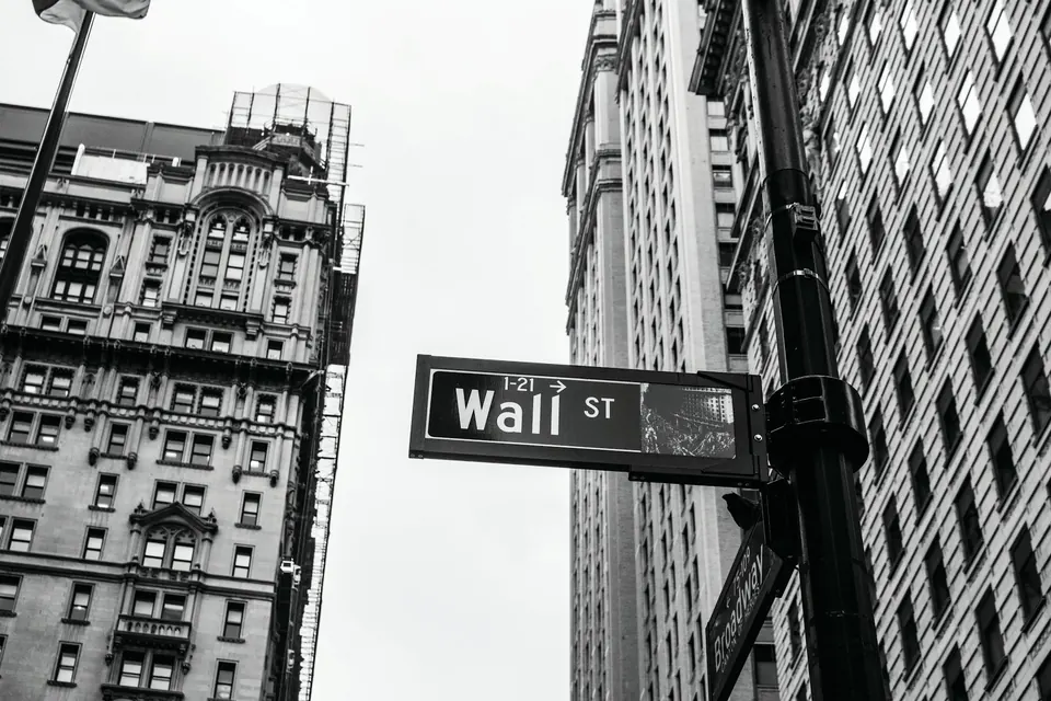 Black and white photo of a Wall St street sign between tall buildings