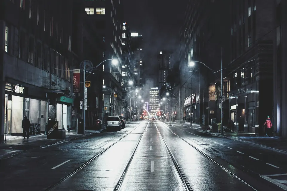 Empty city street at night, lit by street lamps