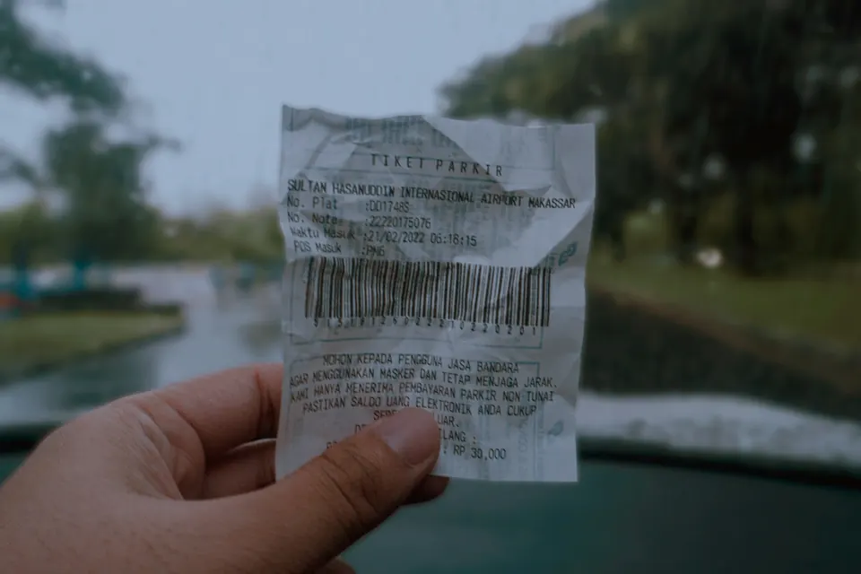 A hand holding up a long shop receipt