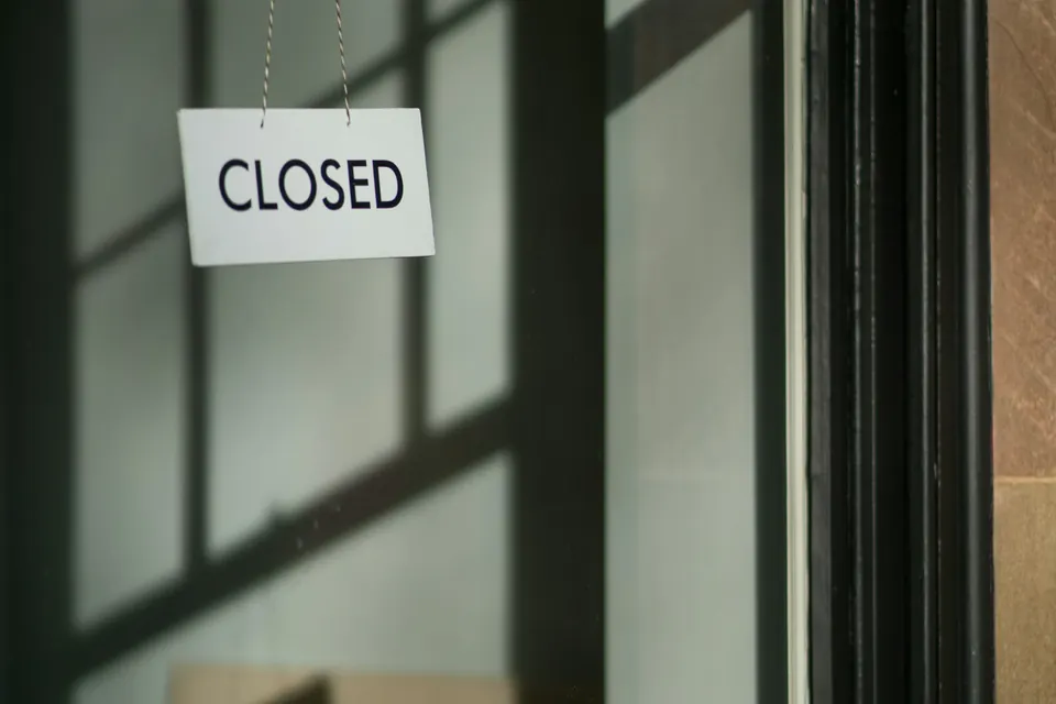 A small closed sign hanging behind a shop door